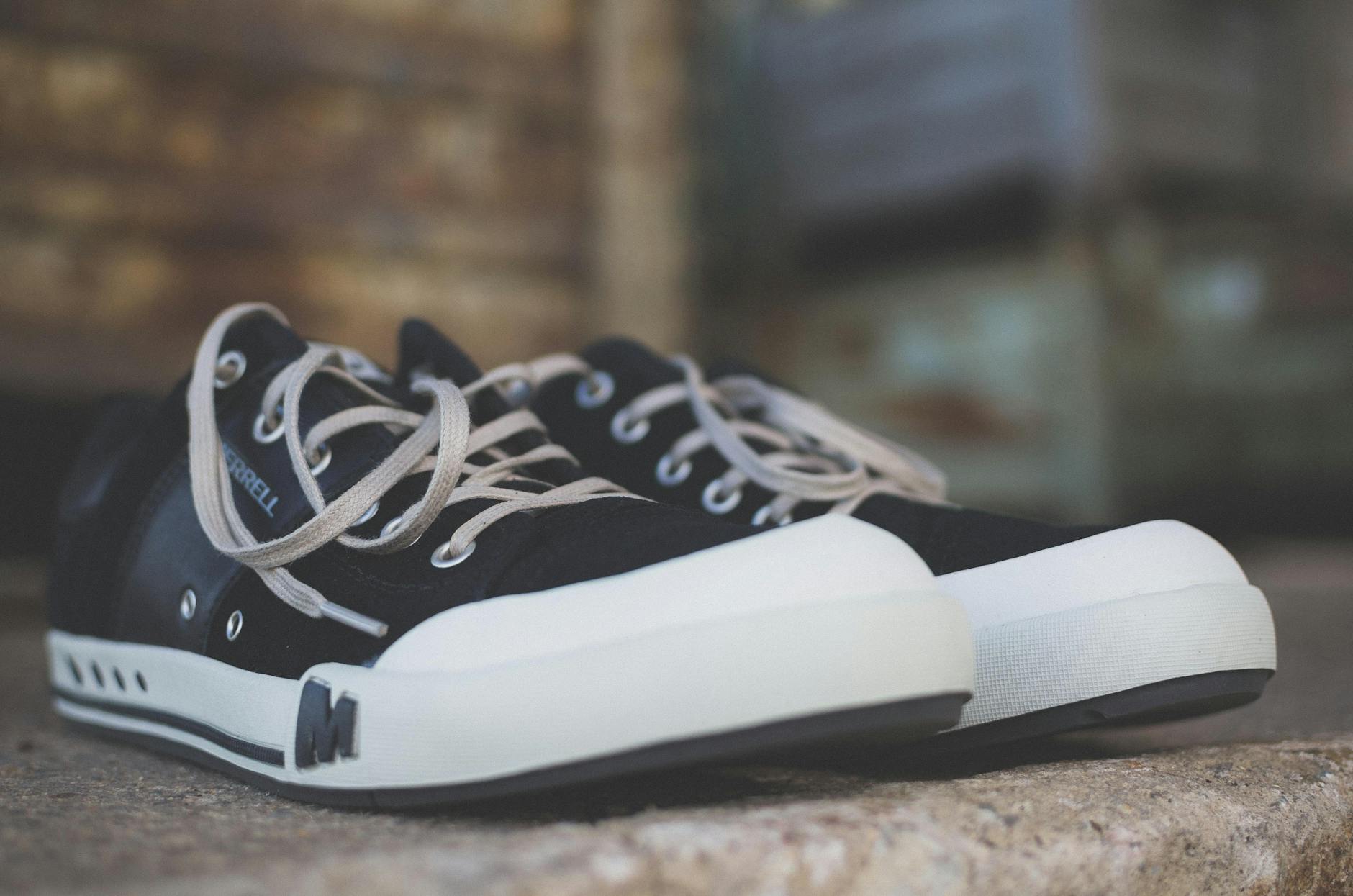 Casual black and white sneakers positioned on a rustic stone surface, showcasing classic style.