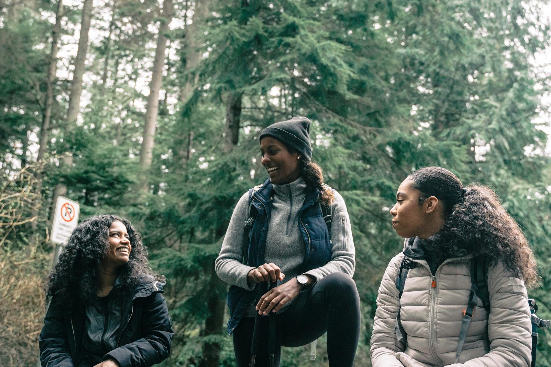 Three women enjoying a relaxing break during a forest hike, smiling and chatting.